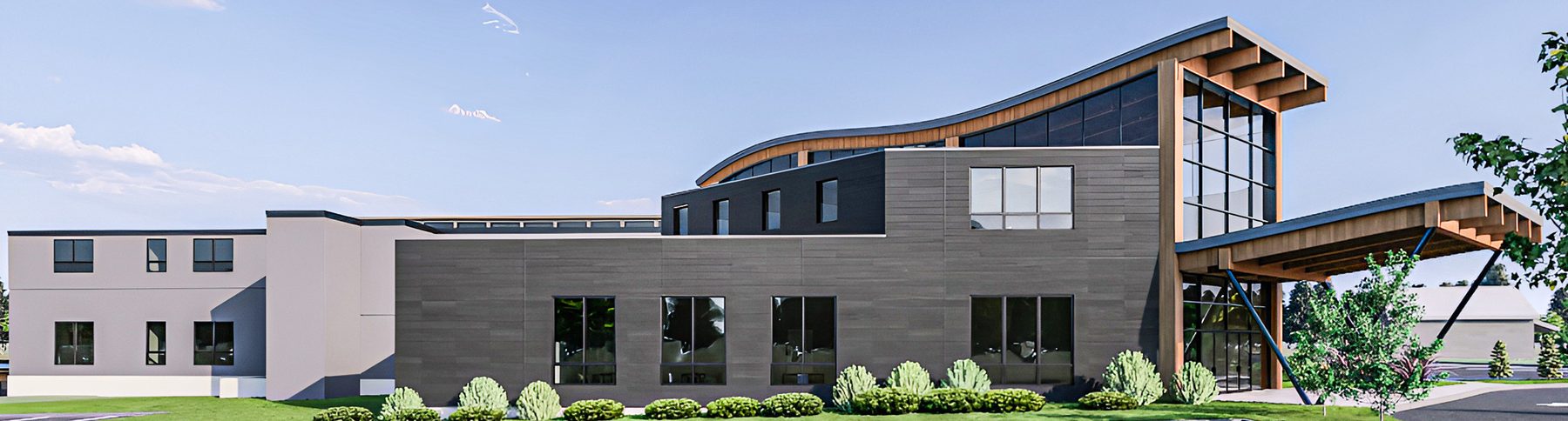 The full length of the building from the front: a tall curved-roof entry at one end with residential wings extending away.